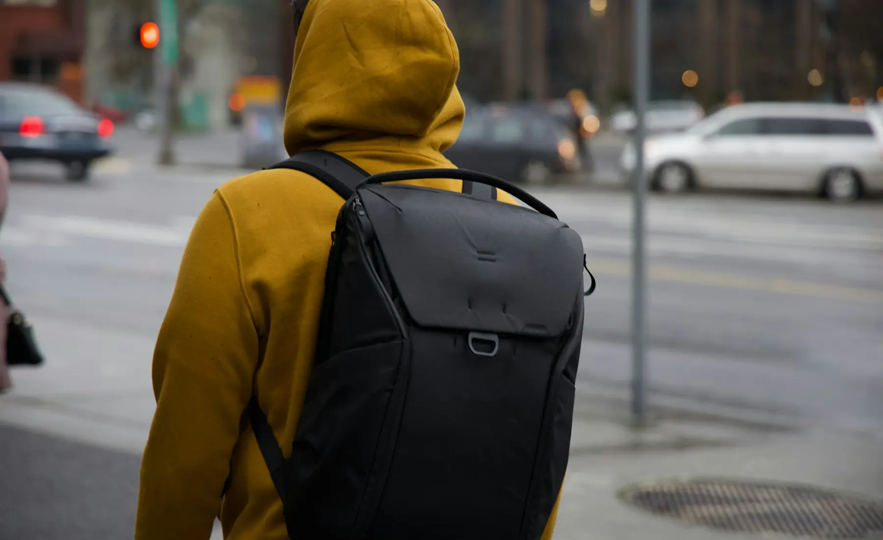 A person in a yellow hoodie with a backpack on a city street